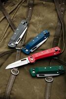 Folding multitool penknives on a khaki canvas backpack. A pocket-sized tool for hiking and daily life. photo