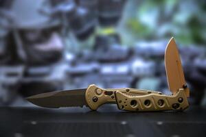 Khaki military pocket folding knives. Compact metal sharp knife with a folding blade. Blurred back. photo