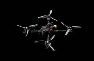 Modern FPV drone on a black background. Four-engine aircraft on the radio control. Drone for racing, filming and entertainment. photo