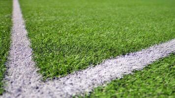 Artificial football turf with a white dividing line. Texture of Perfect green lawn on the football field. photo
