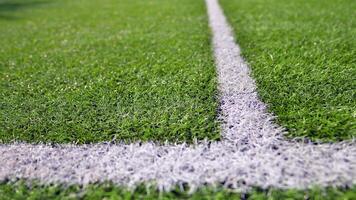 Artificial football turf with a white dividing line. Texture of Perfect green lawn on the football field. photo