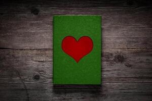 Green paper with a red heart on an old wooden background. Love card concept. Valentine's Day. photo