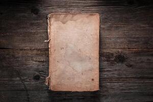 Closed book on vintage wooden background. Old book on the wooden table. Closed book with empty cover laying on wooden table. photo