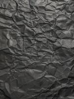 Texture of black crumpled paper. Dark paper background with chaotic bends. A sheet of black wrinkled paper photo