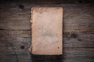 Closed book on vintage wooden background. Old book on the wooden table. Closed book with empty cover laying on wooden table. photo