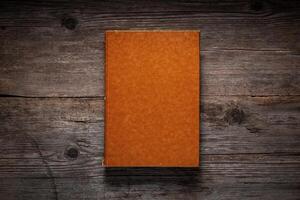 Closed book on vintage wooden background. Old book on the wooden table. Closed book with empty cover laying on wooden table. photo