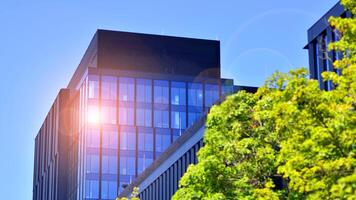 City life, urban landscape and ecology. Modern office complex with glass facades and smooth lines against backdrop of green trees, concept of modern architecture. Organically building into nature. photo