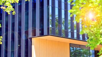 City life, urban landscape and ecology. Modern office complex with glass facades and smooth lines against backdrop of green trees, concept of modern architecture. Organically building into nature. photo