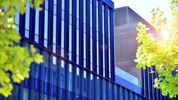 City life, urban landscape and ecology. Modern office complex with glass facades and smooth lines against backdrop of green trees, concept of modern architecture. Organically building into nature. photo