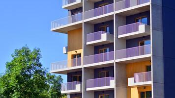 New modern block of flats in green area. Eco apartment building saving energy and fresh air concept. Green tree and new apartment building. The harmony of nature and modernity. photo