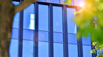 City life, urban landscape and ecology. Modern office complex with glass facades and smooth lines against backdrop of green trees, concept of modern architecture. Organically building into nature. photo