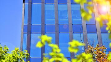 City life, urban landscape and ecology. Modern office complex with glass facades and smooth lines against backdrop of green trees, concept of modern architecture. Organically building into nature. photo