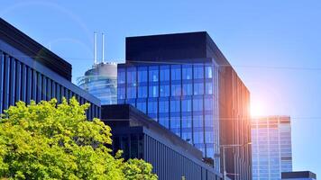 City life, urban landscape and ecology. Modern office complex with glass facades and smooth lines against backdrop of green trees, concept of modern architecture. Organically building into nature. photo