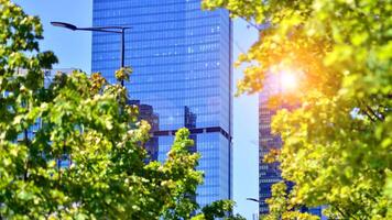 City life, urban landscape and ecology. Modern office complex with glass facades and smooth lines against backdrop of green trees, concept of modern architecture. Organically building into nature. photo