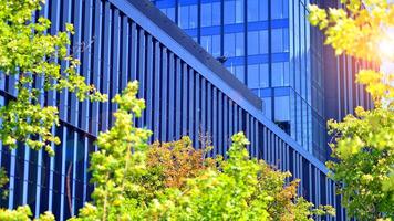 City life, urban landscape and ecology. Modern office complex with glass facades and smooth lines against backdrop of green trees, concept of modern architecture. Organically building into nature. photo
