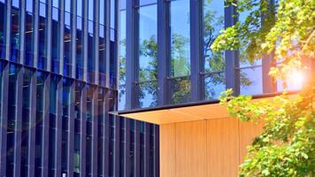 City life, urban landscape and ecology. Modern office complex with glass facades and smooth lines against backdrop of green trees, concept of modern architecture. Organically building into nature. photo