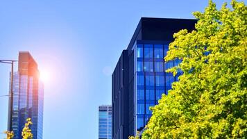 City life, urban landscape and ecology. Modern office complex with glass facades and smooth lines against backdrop of green trees, concept of modern architecture. Organically building into nature. photo