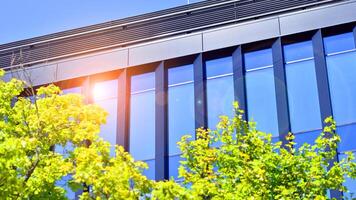 City life, urban landscape and ecology. Modern office complex with glass facades and smooth lines against backdrop of green trees, concept of modern architecture. Organically building into nature. photo