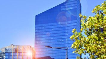 City life, urban landscape and ecology. Modern office complex with glass facades and smooth lines against backdrop of green trees, concept of modern architecture. Organically building into nature. photo