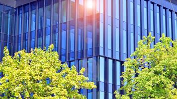 City life, urban landscape and ecology. Modern office complex with glass facades and smooth lines against backdrop of green trees, concept of modern architecture. Organically building into nature. photo