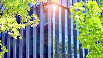City life, urban landscape and ecology. Modern office complex with glass facades and smooth lines against backdrop of green trees, concept of modern architecture. Organically building into nature. photo