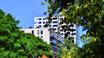 New modern block of flats in green area. Eco apartment building saving energy and fresh air concept. Green tree and new apartment building. The harmony of nature and modernity. photo
