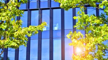 City life, urban landscape and ecology. Modern office complex with glass facades and smooth lines against backdrop of green trees, concept of modern architecture. Organically building into nature. photo
