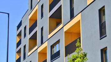 New modern block of flats in green area. Eco apartment building saving energy and fresh air concept. Green tree and new apartment building. The harmony of nature and modernity. photo