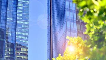 City life, urban landscape and ecology. Modern office complex with glass facades and smooth lines against backdrop of green trees, concept of modern architecture. Organically building into nature. photo