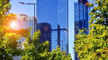 City life, urban landscape and ecology. Modern office complex with glass facades and smooth lines against backdrop of green trees, concept of modern architecture. Organically building into nature. photo