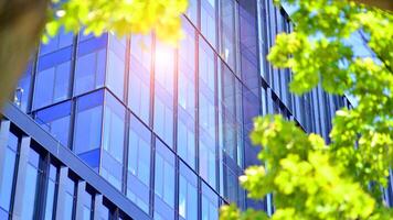 City life, urban landscape and ecology. Modern office complex with glass facades and smooth lines against backdrop of green trees, concept of modern architecture. Organically building into nature. photo