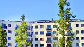 New modern block of flats in green area. Eco apartment building saving energy and fresh air concept. Green tree and new apartment building. The harmony of nature and modernity. photo