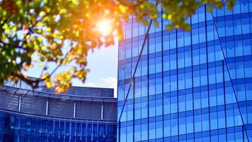 City life, urban landscape and ecology. Modern office complex with glass facades and smooth lines against backdrop of green trees, concept of modern architecture. Organically building into nature. photo