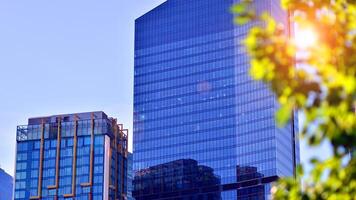 City life, urban landscape and ecology. Modern office complex with glass facades and smooth lines against backdrop of green trees, concept of modern architecture. Organically building into nature. photo