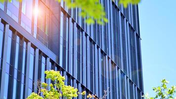 City life, urban landscape and ecology. Modern office complex with glass facades and smooth lines against backdrop of green trees, concept of modern architecture. Organically building into nature. photo