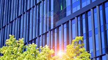 City life, urban landscape and ecology. Modern office complex with glass facades and smooth lines against backdrop of green trees, concept of modern architecture. Organically building into nature. photo