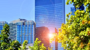 City life, urban landscape and ecology. Modern office complex with glass facades and smooth lines against backdrop of green trees, concept of modern architecture. Organically building into nature. photo
