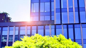 City life, urban landscape and ecology. Modern office complex with glass facades and smooth lines against backdrop of green trees, concept of modern architecture. Organically building into nature. photo