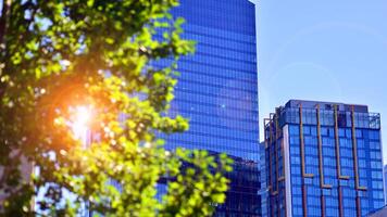 City life, urban landscape and ecology. Modern office complex with glass facades and smooth lines against backdrop of green trees, concept of modern architecture. Organically building into nature. photo