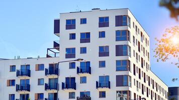 New modern block of flats in green area. Eco apartment building saving energy and fresh air concept. Green tree and new apartment building. The harmony of nature and modernity. photo