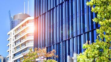 City life, urban landscape and ecology. Modern office complex with glass facades and smooth lines against backdrop of green trees, concept of modern architecture. Organically building into nature. photo