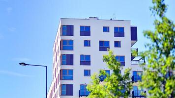 New modern block of flats in green area. Eco apartment building saving energy and fresh air concept. Green tree and new apartment building. The harmony of nature and modernity. photo