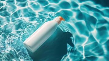 A bottle of lotion floats on the surface of a clear blue pool photo