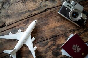 A passport a camera and a model airplane are positioned on a wooden surface suggesting a preparation for travel photo