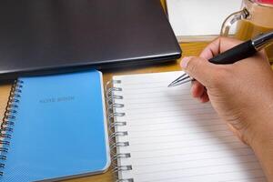 Hands holding pencils and notebooks. Hand with a pen is writing in a notebook. Mock-up Concept. photo