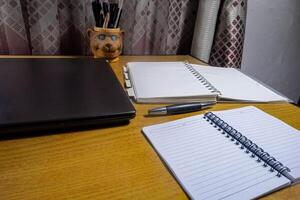 Office table with blank notebook, pen and laptop. office desk top view with blank notebook photo