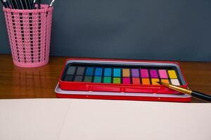 Blank sketchbook, color palette and a set brush, top view photo