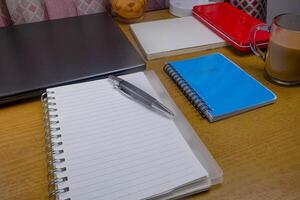 Office table with blank notebook, pen and laptop. office desk top view with blank notebook photo