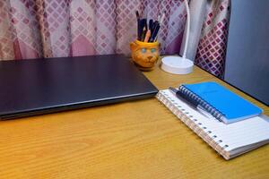 Office table with blank notebook, pen and laptop. office desk top view with blank notebook photo