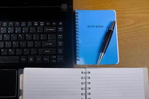 Office table with blank notebook, pen and laptop. office desk top view with blank notebook photo